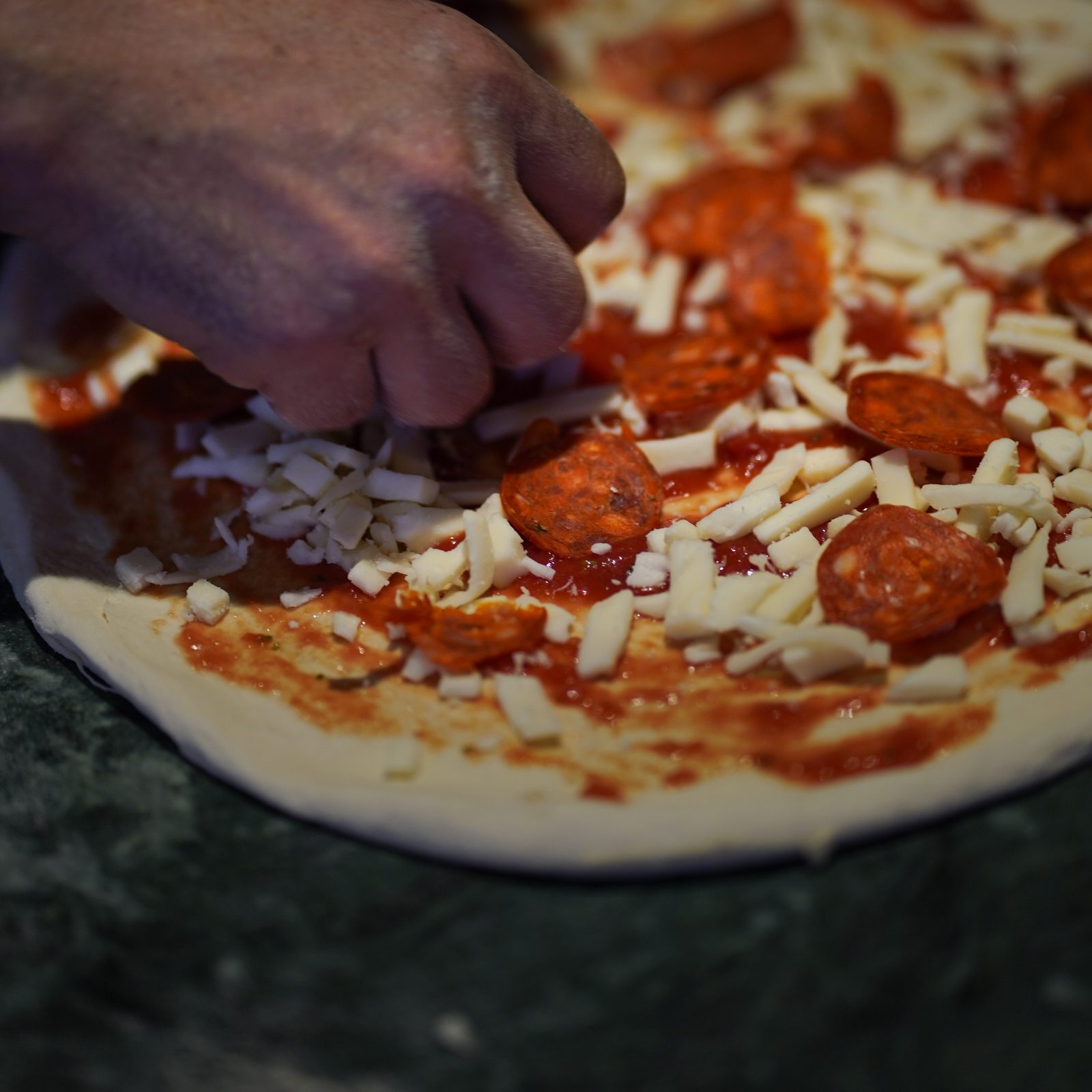 Le pizzaiolo garnit une pizza à la main